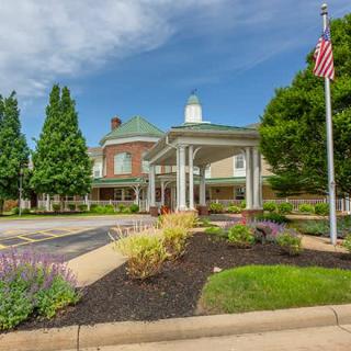 A well-maintained building entrance with landscaping and an American flag on a clear day.