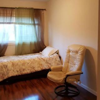 A cozy bedroom with a single bed and an armchair by the window.
