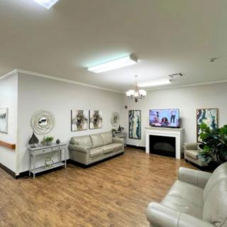 A cozy living room with modern decor featuring sofas, a TV above a fireplace, and wooden flooring.