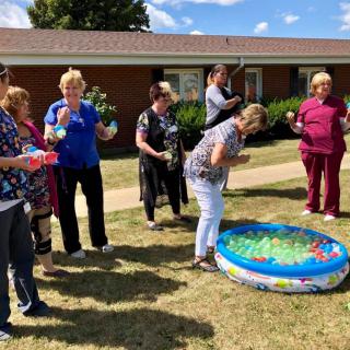 A group of people enjoying an outdoor activity with a small pool filled with colorful items.