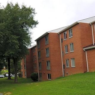 A brick apartment building surrounded by trees and grass.