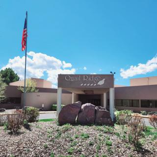 The entrance of a public library with an American flag flying nearby.