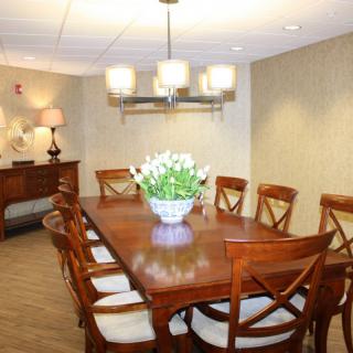 A stylish dining room with a wooden table and chairs, complemented by a chandelier and a centerpiece of flowers.