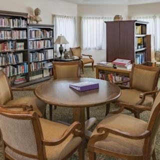A cozy reading area in a library with bookshelves and seating around a table.