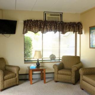 A cozy living room with chairs, a television, and a window with curtains.