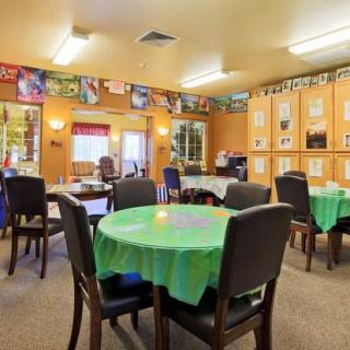 A cozy dining room with tables and chairs, decorated with tablecloths and wall hangings.