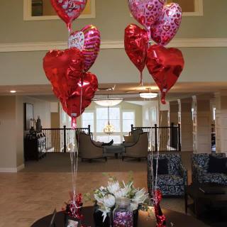 Red and pink heart-shaped balloons arranged in a lobby area.