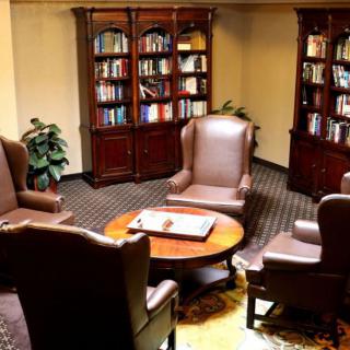 A cozy reading room with leather armchairs and wooden bookshelves filled with books.
