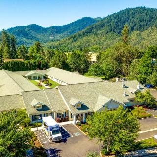 Aerial view of a building complex surrounded by lush greenery and mountainous landscape.