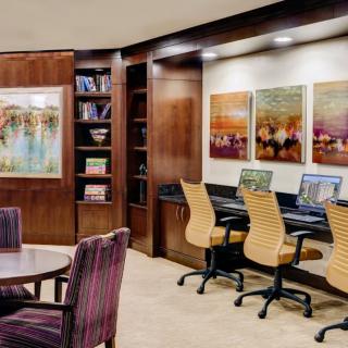 A modern office space with computers, bookshelves, and a meeting area featuring contemporary artwork.
