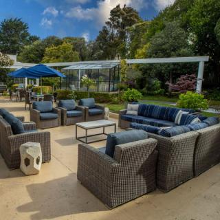 A spacious outdoor patio with comfortable seating arrangements surrounded by lush greenery.