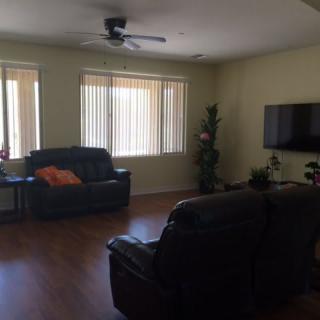 A cozy living room with sofas, a wall-mounted television, and large windows.