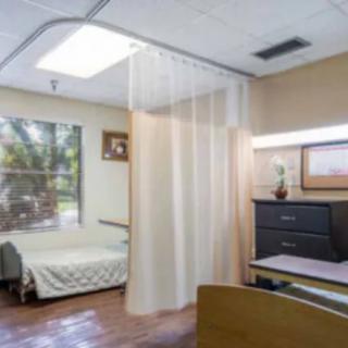 A hospital room featuring a bed, privacy curtain, and a window with natural light.