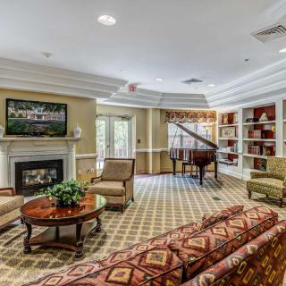 A cozy living room with a grand piano, fireplace, and comfortable seating.