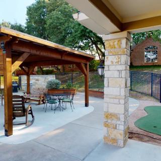 A cozy backyard with a wooden gazebo, outdoor seating, and landscaped surroundings.