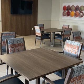 A modern dining area with neatly arranged tables and chairs, featuring wall art and a television.