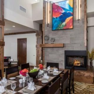 A modern dining room with a well-set table, vibrant artwork, and a cozy fireplace.