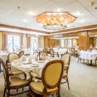 An elegant dining room with formal table settings and a chandelier.