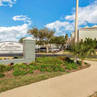 A landscaped area with a sign near a building under a partly cloudy sky.