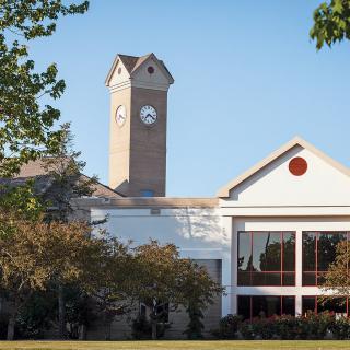 A building with a clock tower surrounded by trees under a clear blue sky.