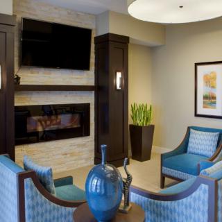 A modern living room with a fireplace, TV, and blue seating.