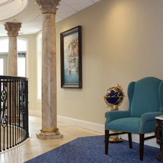 Elegant interior with a blue chair, marble columns, and framed artwork.