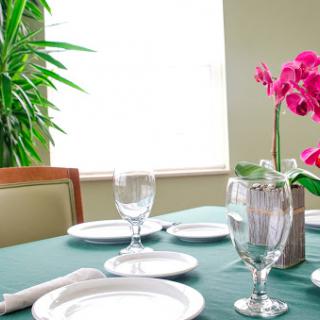 A beautifully arranged dining table featuring elegant dinnerware and a vibrant floral centerpiece.