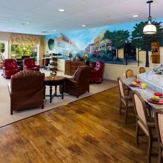 A cozy living area with armchairs and a mural, adjacent to a kitchen counter with seating.