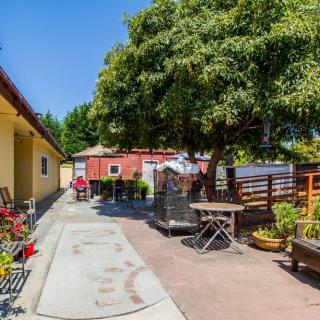 A peaceful backyard with a patio area, chairs, tables, and lush green trees.