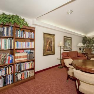 A cozy living room with a well-stocked bookshelf, comfortable seating, and decorative artwork.