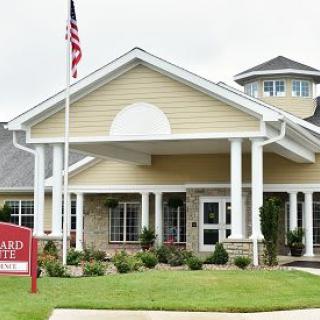 A building entrance with columns, an American flag, and a well-maintained lawn.