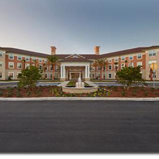 Front view of a large hotel with a fountain and landscaped entrance.