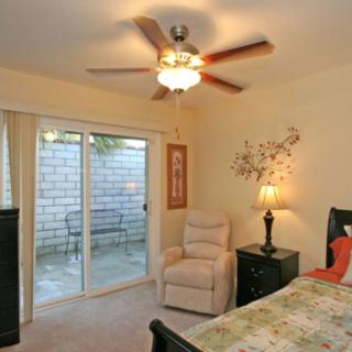 A cozy bedroom with a ceiling fan, sliding doors, and comfortable furnishings.