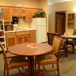 A cozy kitchen and dining area featuring a wooden table and chairs, with modern appliances in the background.