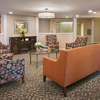 A cozy living room with patterned chairs, an orange sofa, and a coffee table.