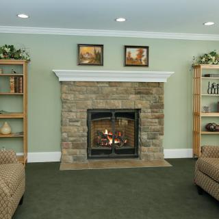 A cozy living room with a stone fireplace flanked by bookshelves and armchairs.