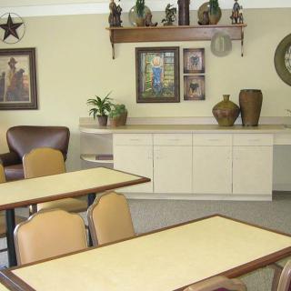 A cozy dining area with tables, chairs, wall decor, and ornamental vases.