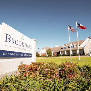 A Brookdale senior living community with flags and a landscaped entrance.