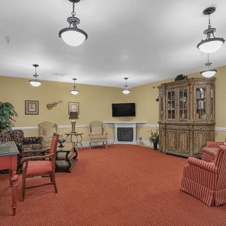A cozy living room with comfortable seating, a large cabinet, and a television.