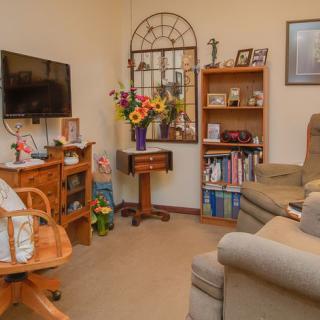 A cozy living room with comfortable seating, a television, and shelves filled with books and decorative items.