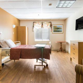 A clean and well-lit hospital patient room equipped with essential furniture.