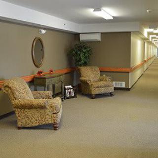 A long hallway with patterned chairs and a small table, featuring soft lighting and neutral decor.