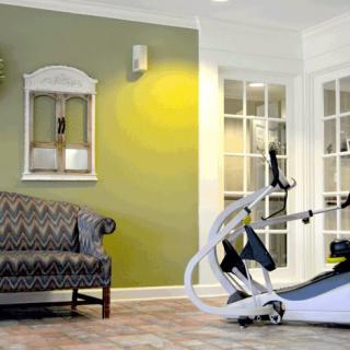 A stylish home gym setup with an elliptical trainer and a comfortable sofa in the living area.