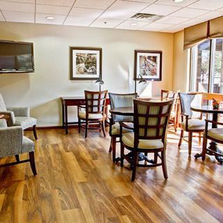 A cozy lounge area with tables, chairs, and artwork on the walls.