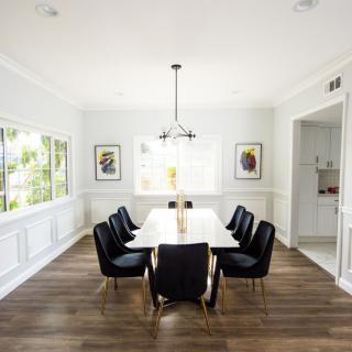 A modern dining room with a large table, black chairs, and elegant decor.