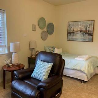 A cozy bedroom featuring a bed, a comfortable chair, and decorative elements on the walls.