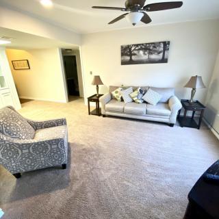 A cozy living room with a sofa, armchair, and ceiling fan.
