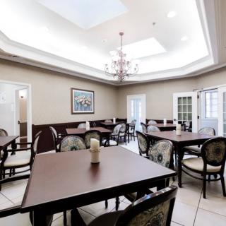 A well-lit dining room featuring multiple tables and chairs, complemented by a chandelier and skylight.