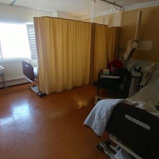 A view of a hospital patient room with beds separated by curtains.