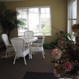 A cozy sunlit dining area with white furniture and decorative plants.